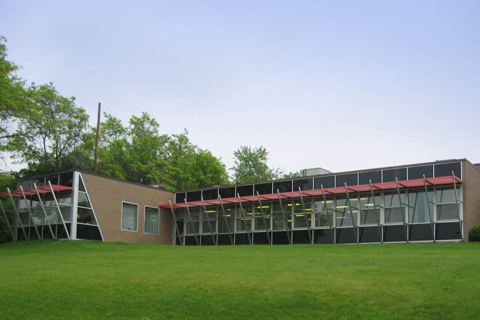 A modern building with large windows and a green lawn under a clear sky.