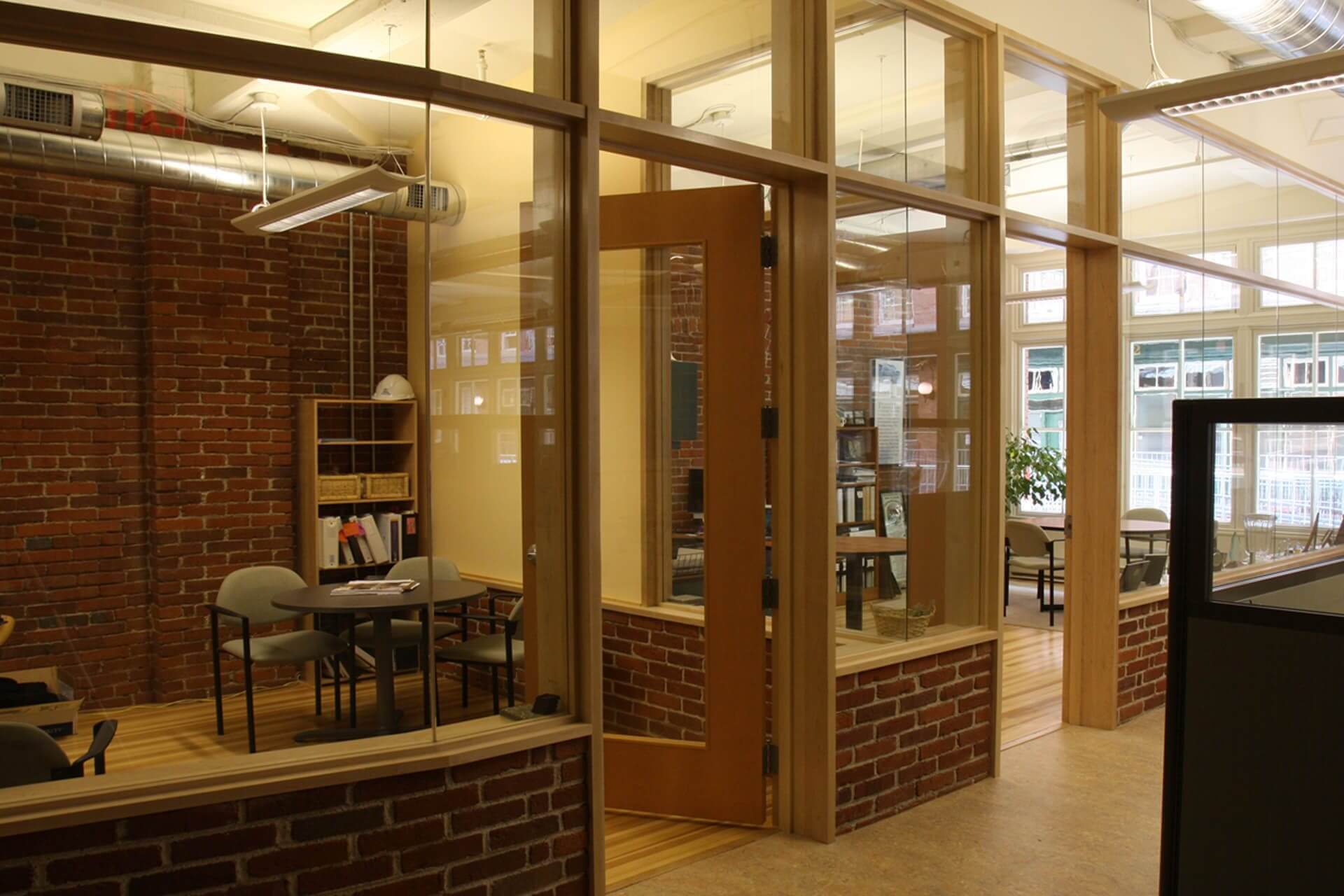 Interior view of a modern office with glass walls and wooden frames.